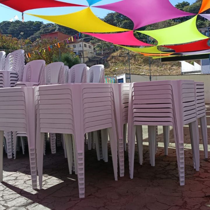 Cadeiras e mesas empilhadas em local de evento decorado
