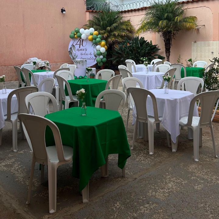 Festa ao ar livre com mesas de toalhas verdes e brancas e cadeiras brancas